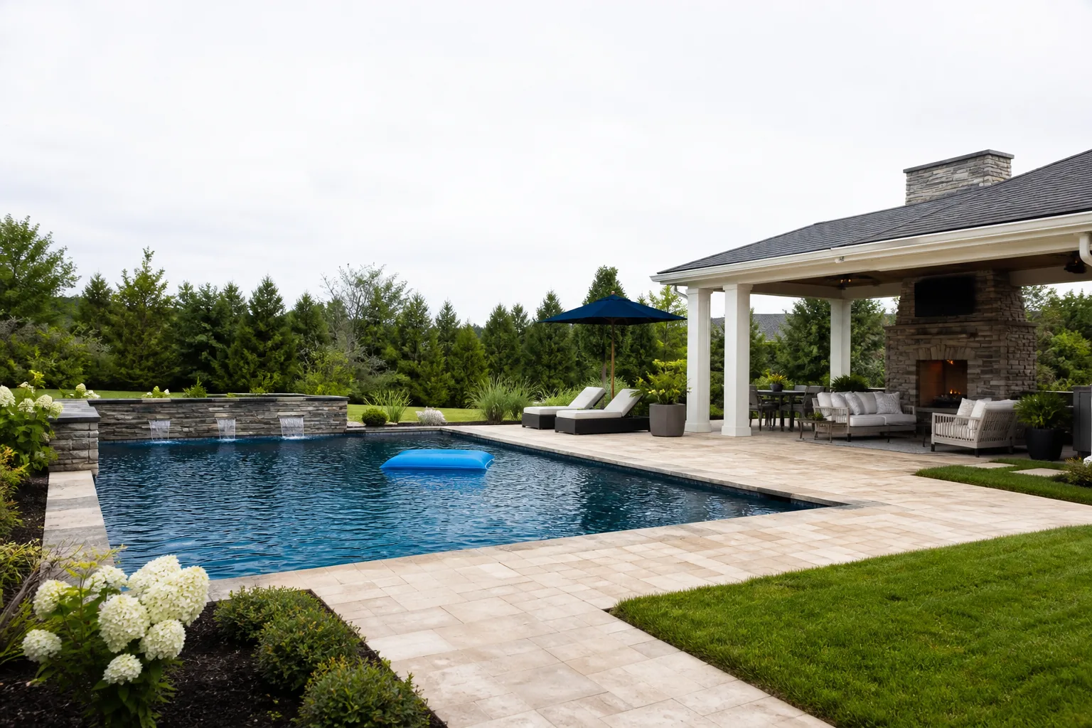 A finished backyard with an inground pool, stone paver patio, planted beds and fresh lawn built as one project